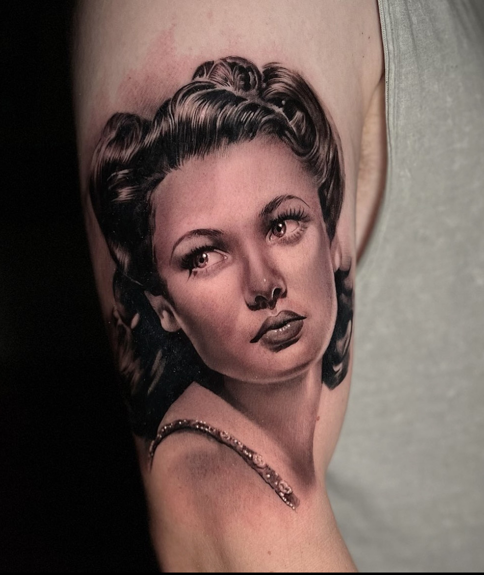 A female tattoo artist sits at a reception desk preparing for a walk-in tattoo